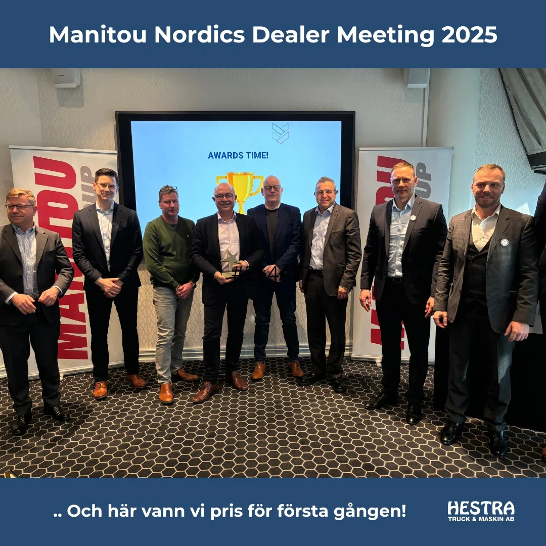 Sju män i affärsdräkt poserar framför en presentationsbild från Awards Time! på Manitou Nordics Dealer-möte 2025, som visar det starka partnerskapet med Hestra Truck.