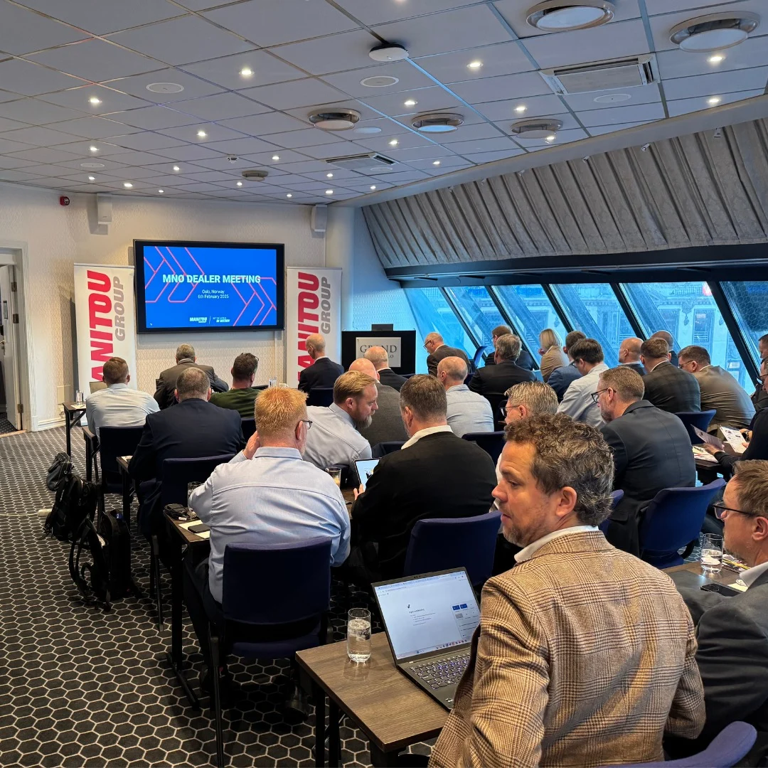 En grupp människor i affärskläder deltar i ett Dealer-möte Oslo i ett modernt konferensrum, vända mot en presentationsskärm längst fram.